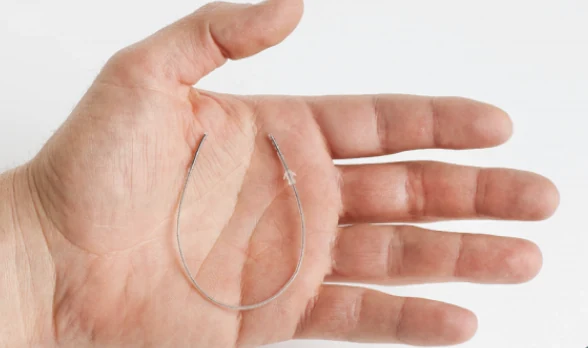 Official StimRouter photograph showing the complete thin implanted lead curved across a person's hand for scale.